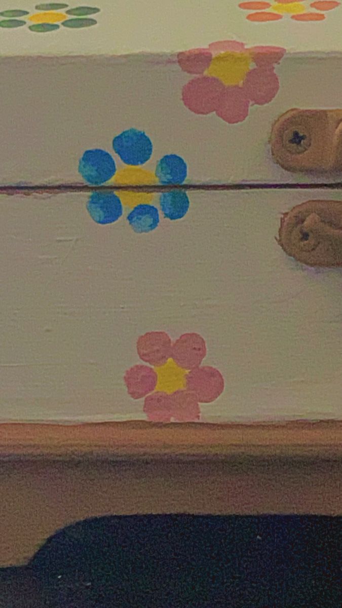 a wooden box with flowers painted on the lid and feet sticking out from underneath it