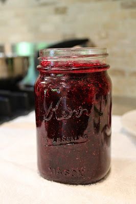 a glass jar filled with red liquid sitting on top of a white towel next to a stove