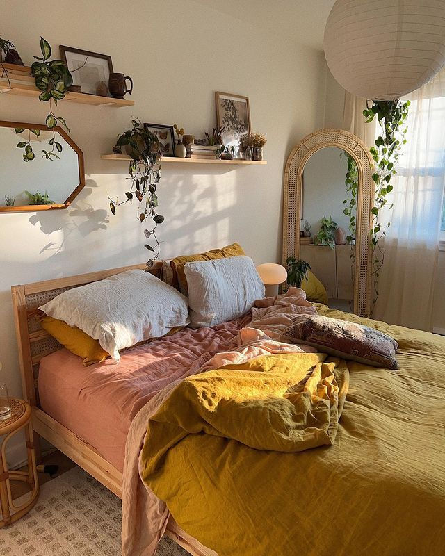 a bed room with a neatly made bed and some plants on the wall above it