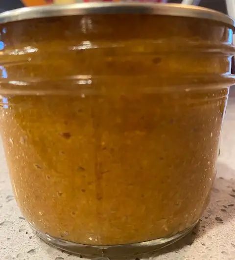 a glass jar filled with peanut butter sitting on top of a counter next to an orange bowl