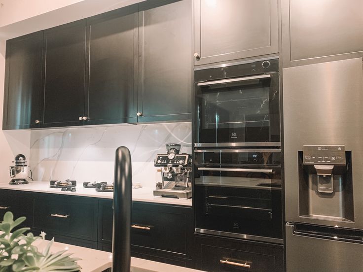 a kitchen with black cabinets and stainless steel appliances