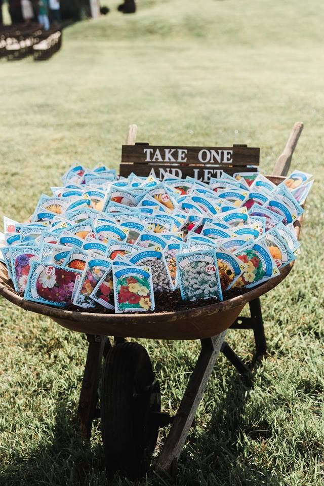 an old wheelbarrow filled with quilts on top of green grass next to a sign that says take one and let