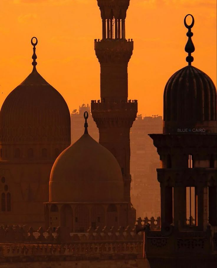 the silhouette of two large buildings against an orange sky