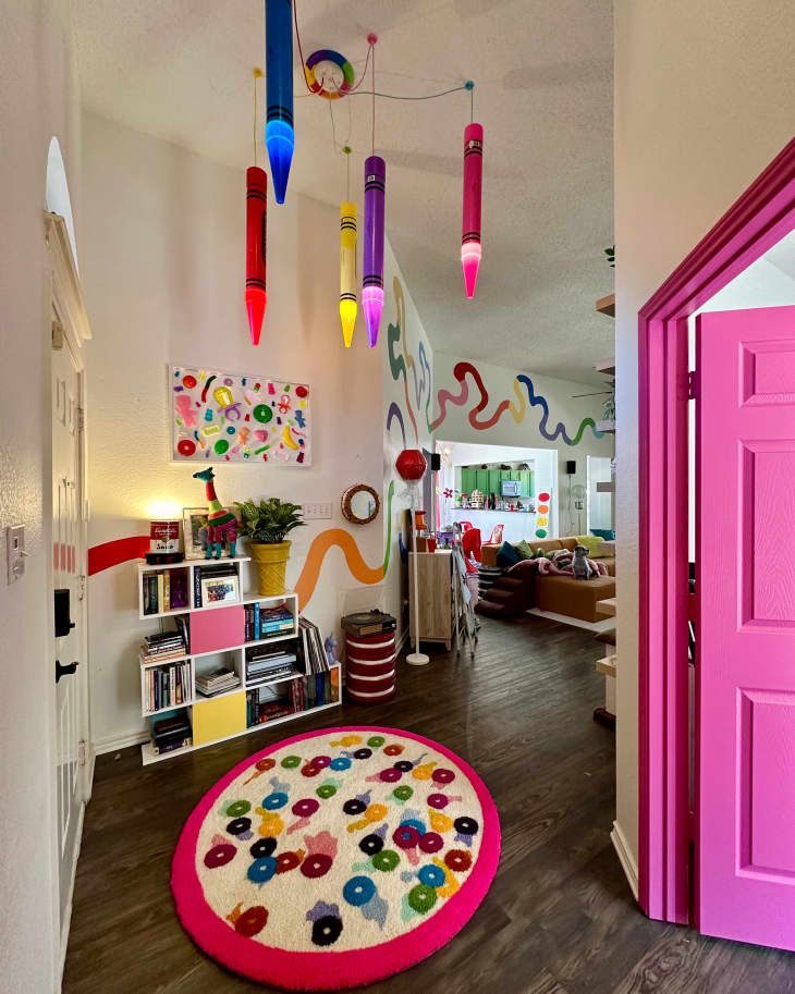 a brightly colored room with pink door and colorful rug on the floor in front of it