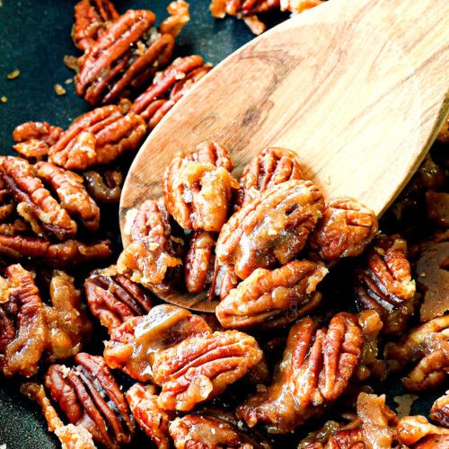 a wooden spoon full of pecans sitting on top of a table