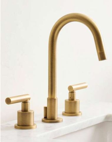 two brass faucets on a white counter top