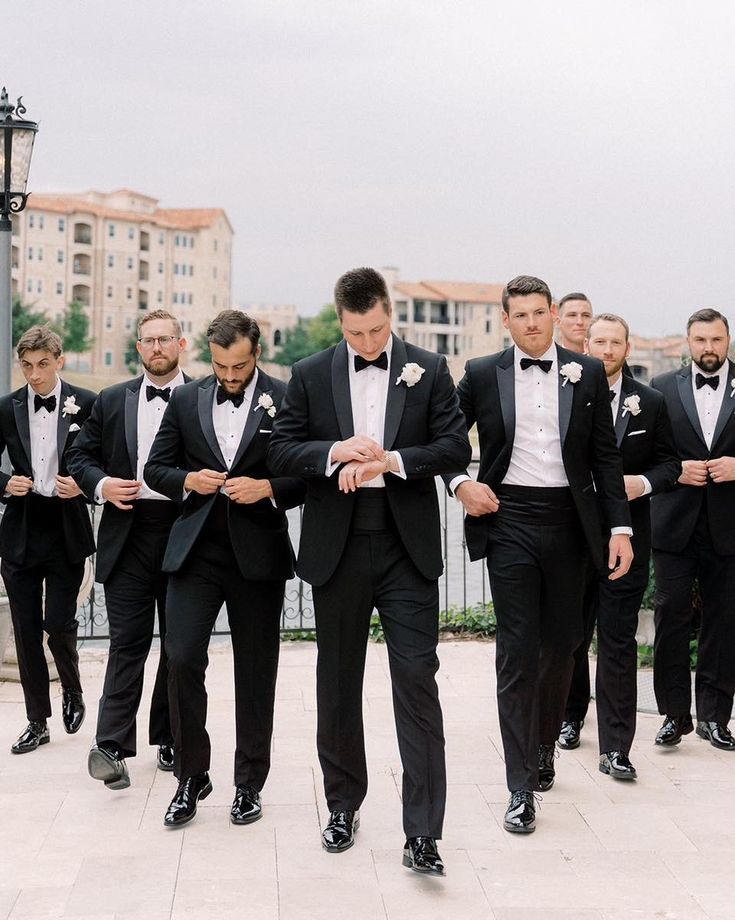 a group of men in tuxedos walking down the street