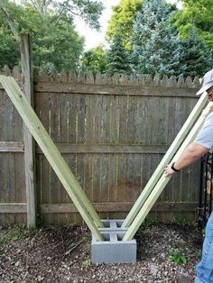 a man standing in front of a wooden fence with two poles sticking out of it