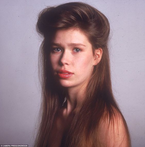 a woman with long brown hair is looking at the camera and has her head tilted back