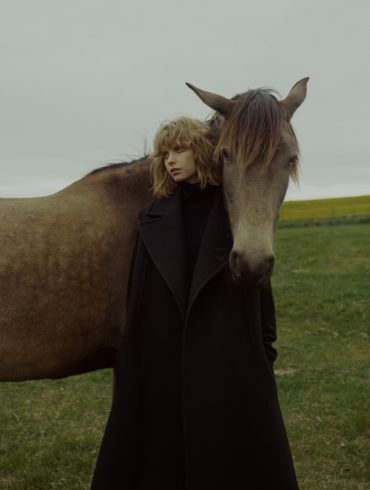 a woman standing next to a horse in a field