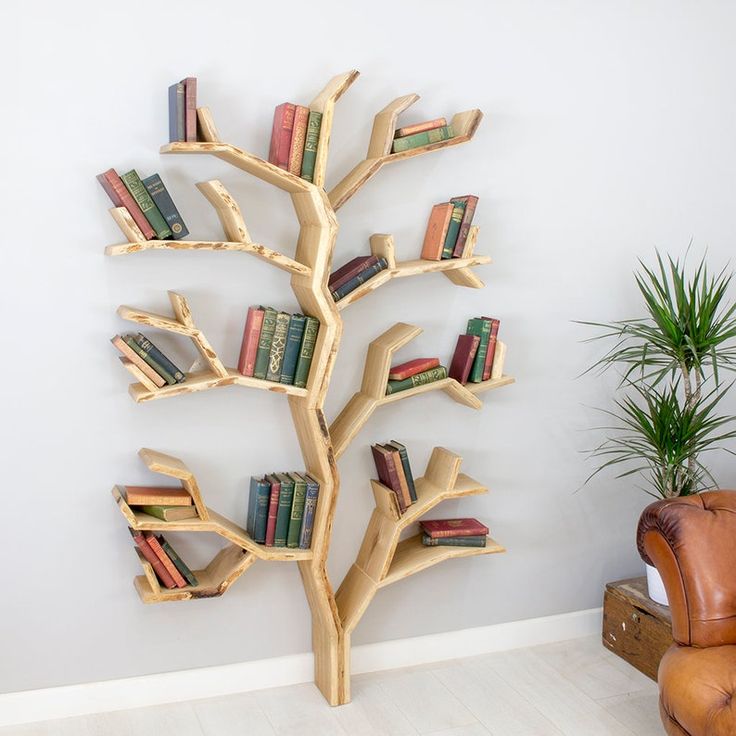 a wooden tree with books on it in front of a wall mounted bookcases