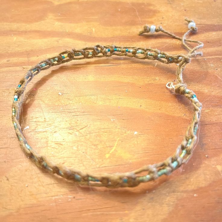 a close up of a bracelet on a wooden table with beads and chains attached to it