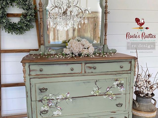 an old dresser with flowers and a mirror on top