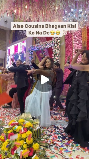 two women dancing in front of a group of people at a party with flowers on the floor