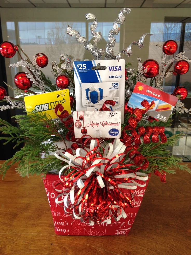 a gift basket with christmas decorations and cards in it on top of a wooden table