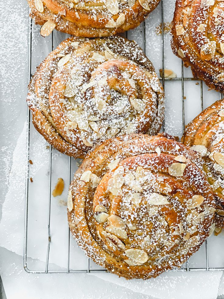 several pastries sitting on top of a cooling rack covered in powdered sugar and nuts