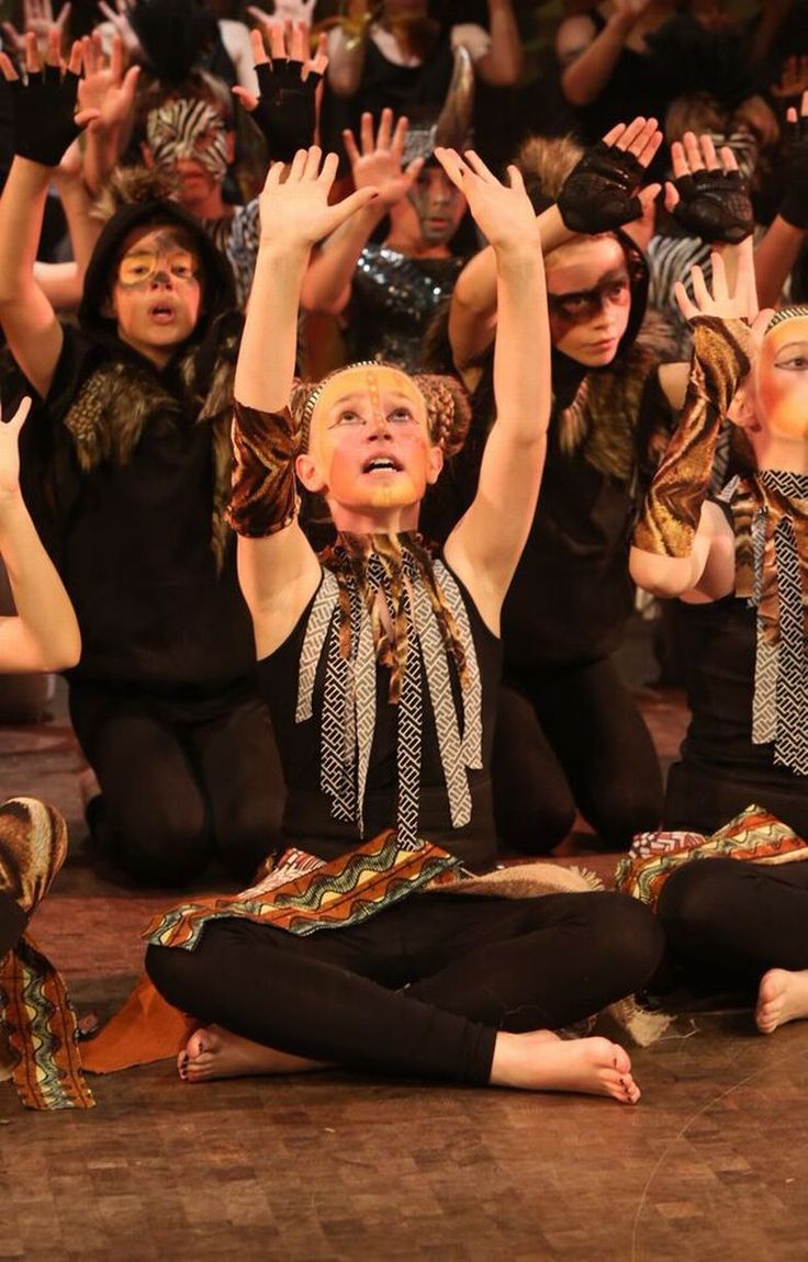 a group of women sitting on the floor with their hands up