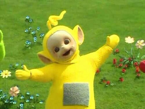 a man in a yellow costume standing on top of a lush green field next to flowers