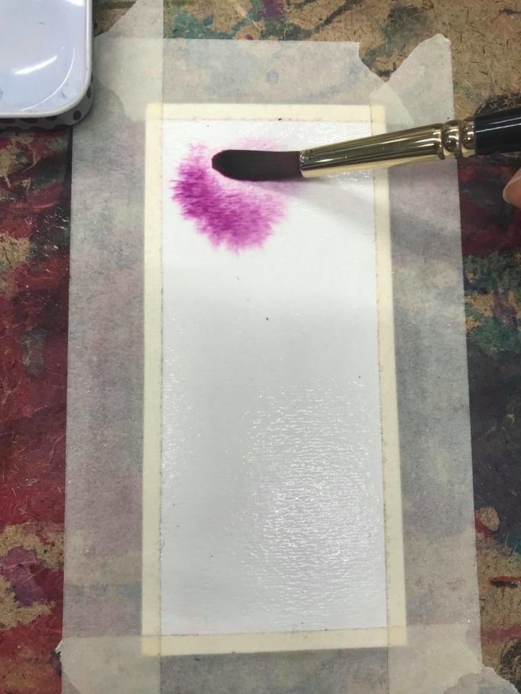 a person using a paint brush on a piece of white paper with purple ink in it