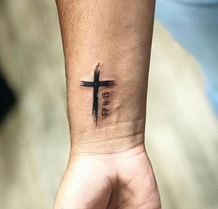 a person with a cross tattoo on their wrist and the word god written in black ink