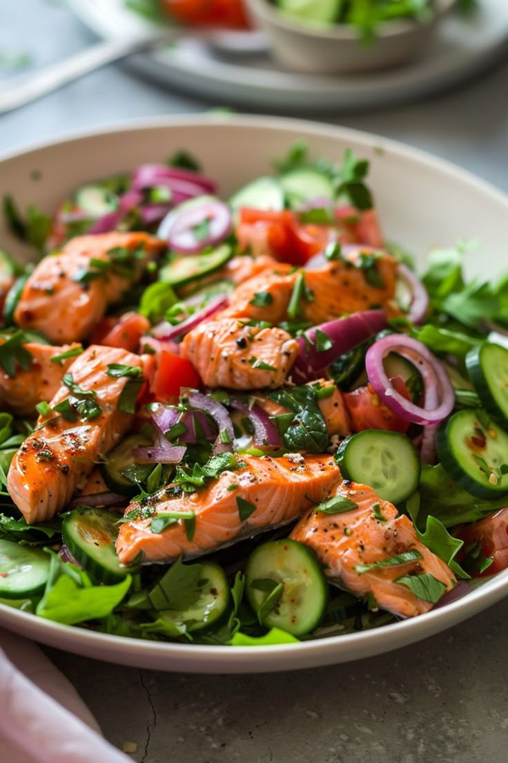 a salad with salmon and cucumbers in a bowl