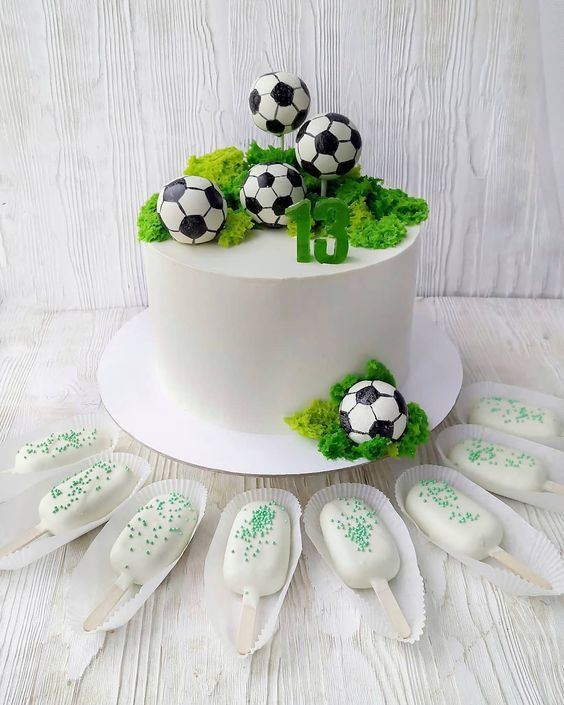 a white cake with soccer themed decorations on top and spoons next to the cake