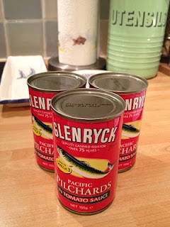 three cans of canned fish food on a kitchen counter