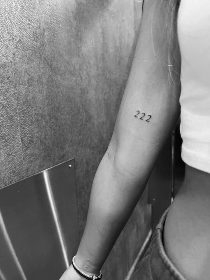 a woman's arm with the number 22 tattoo on her left forearm and numbers written in