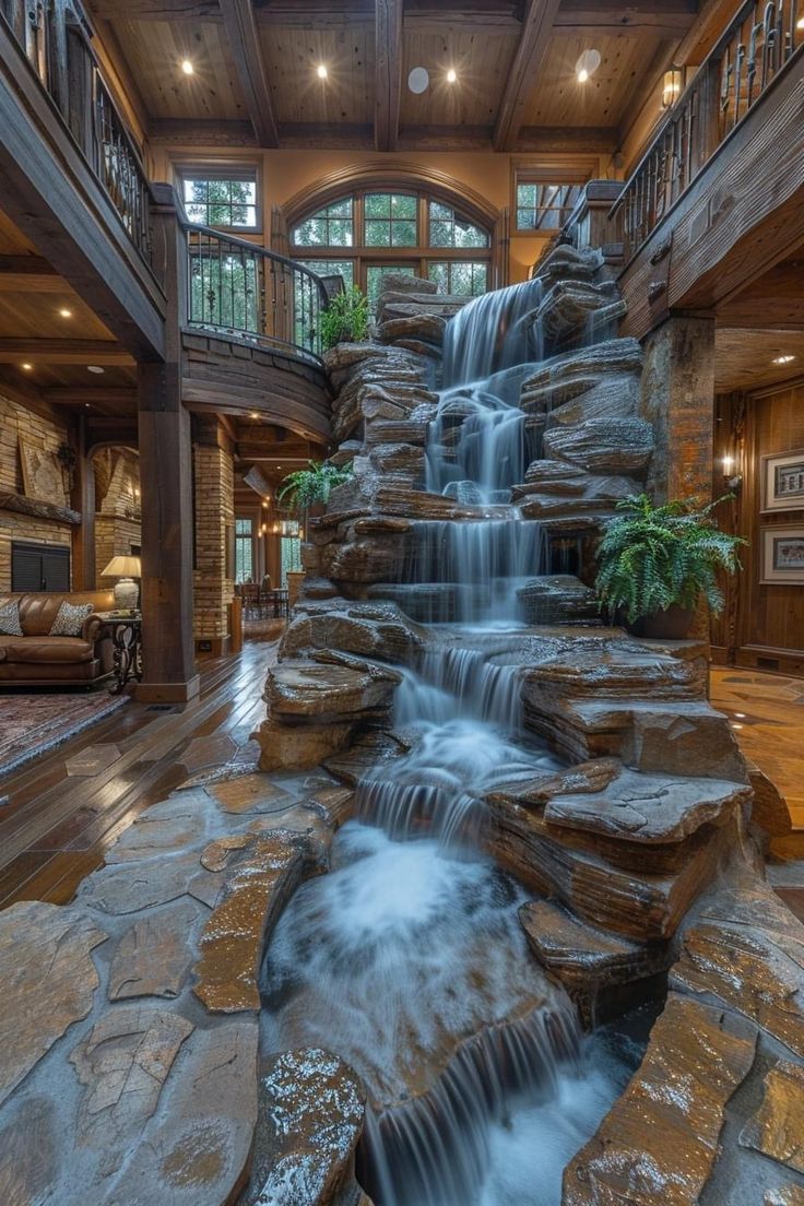 a large waterfall in the middle of a living room filled with furniture and stone steps