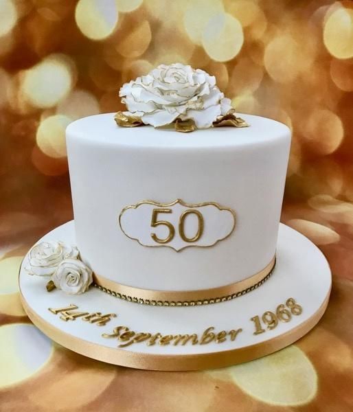 a white and gold 50th birthday cake with flowers