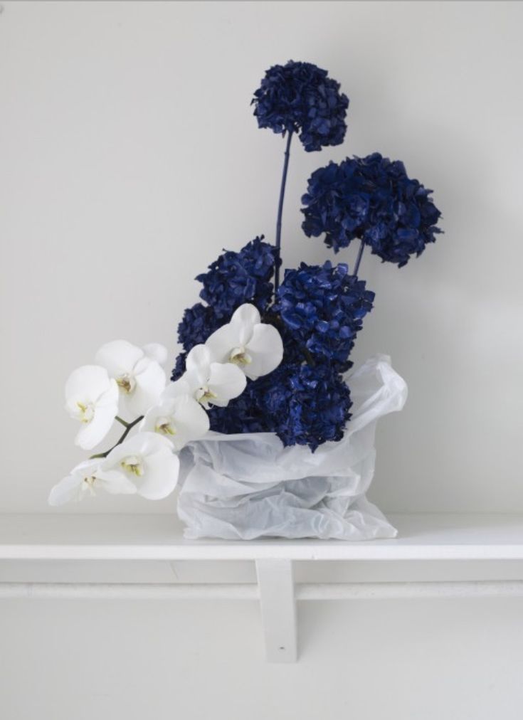 white and blue flowers in a vase on a shelf