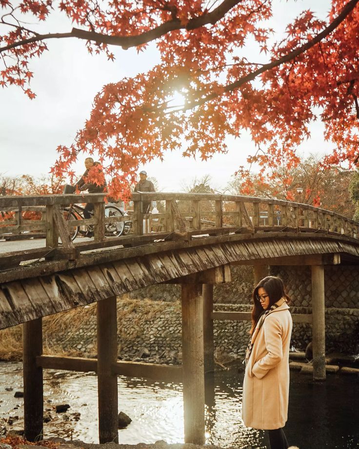 a woman standing on a bridge next to a river