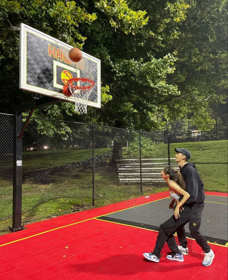 a man and woman playing basketball on an outdoor court