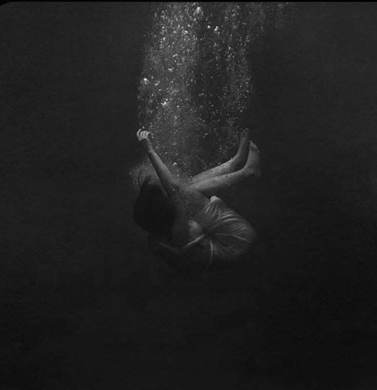 a man swimming under water in the dark