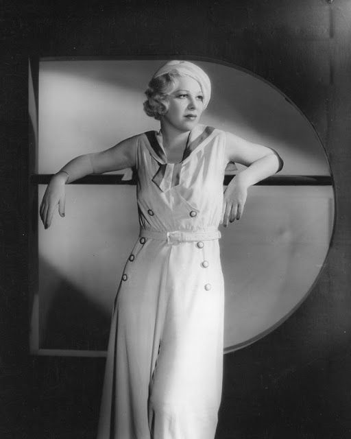 an old photo of a woman posing in front of a round window with her hands on her hips