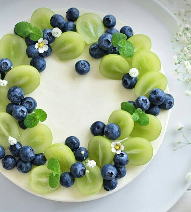 a white cake topped with blueberries and green grapes