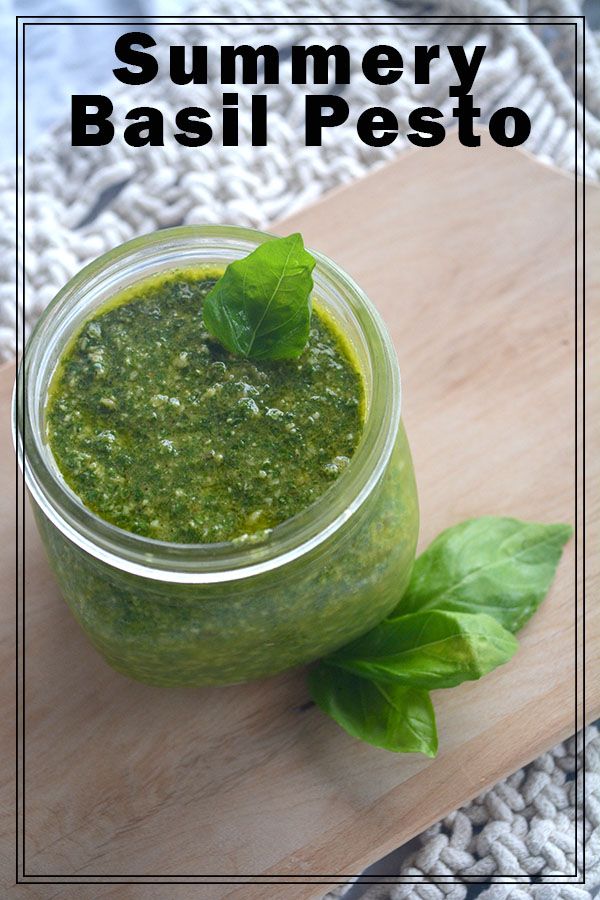 a jar filled with pesto sitting on top of a wooden cutting board