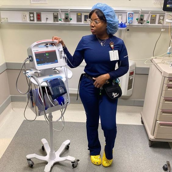 a woman in scrubs standing next to a machine