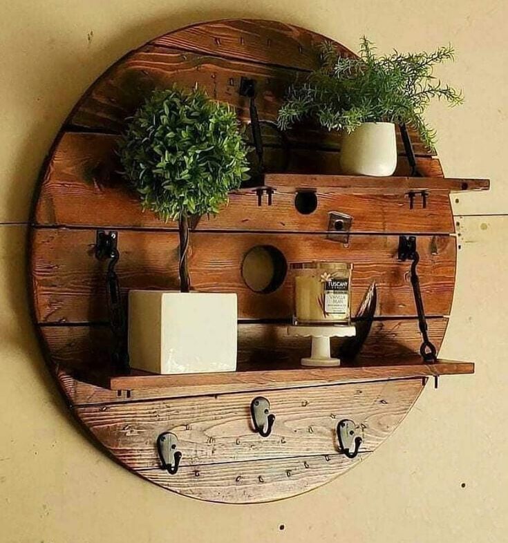 a wooden shelf with two potted plants on it and hooks hanging from the wall