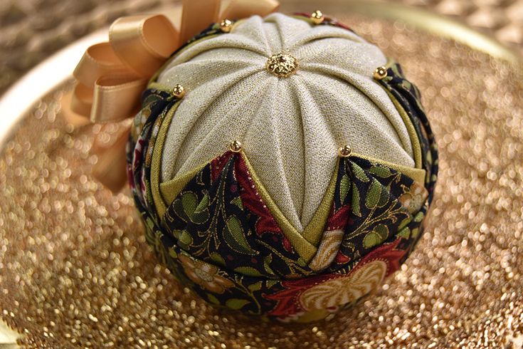 an ornament is sitting on top of a gold plate with ribbon around it