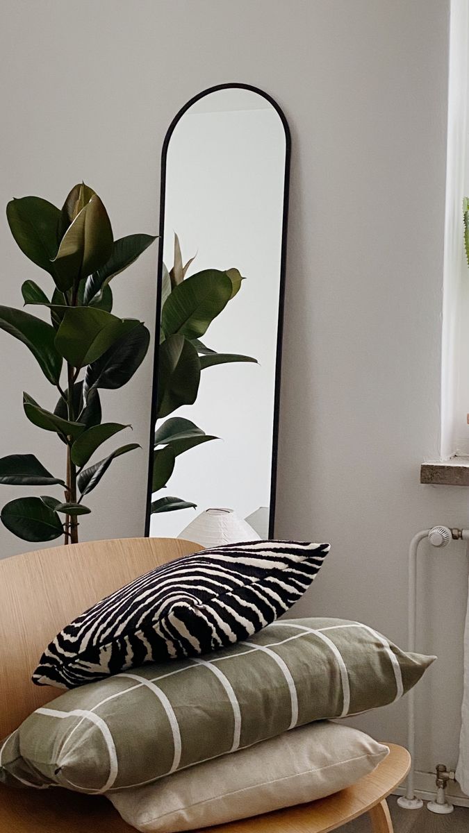 three pillows stacked on top of each other in front of a mirror and potted plant