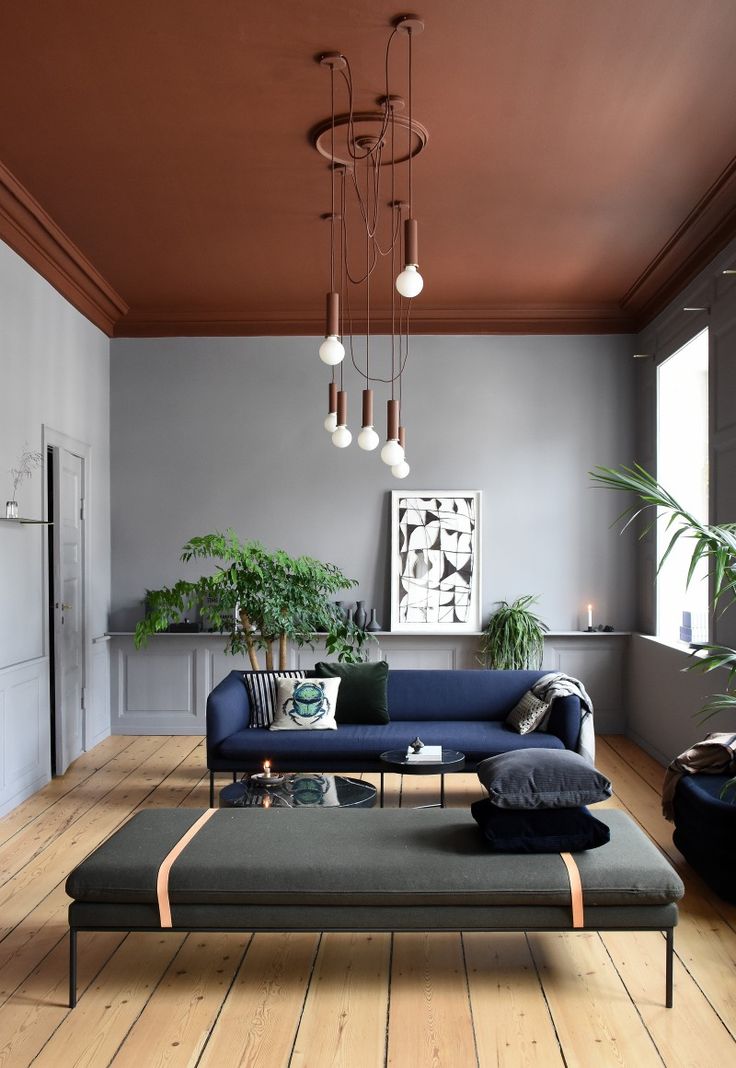 a living room with couches, tables and lamps hanging from the ceiling in front of windows