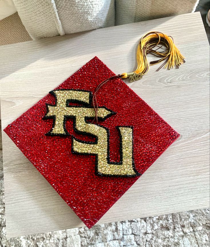 a red and gold ornament sitting on top of a white wooden table next to a pillow