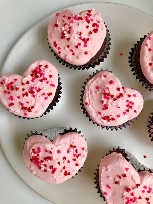 heart shaped cupcakes with pink frosting and sprinkles on a plate