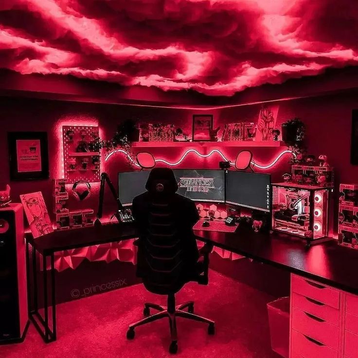 a man sitting at a desk in front of two computer monitors with red lights on them