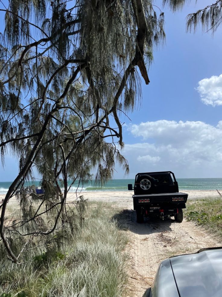 there is a truck parked on the side of the road near the beach and water