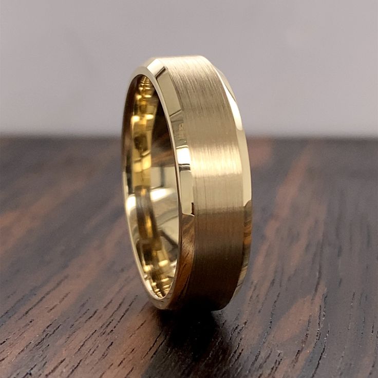 a yellow gold wedding band on top of a wooden table