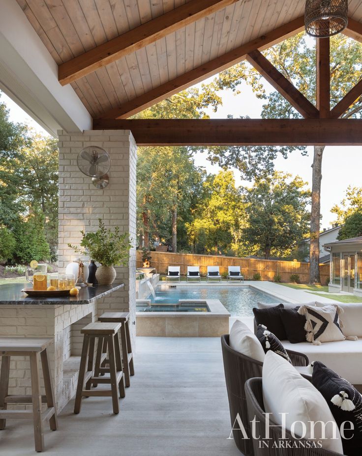 an outdoor kitchen and living room are featured in this photo, while the pool is visible from the dining area