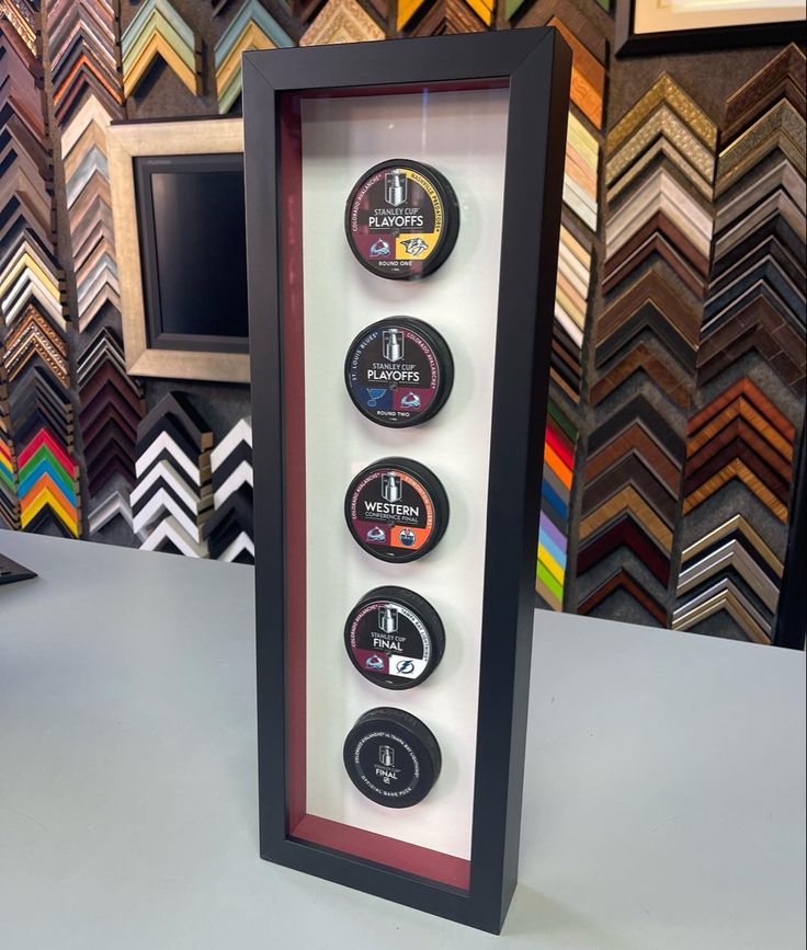 a display case with three different types of buttons in front of a wall of framed pictures