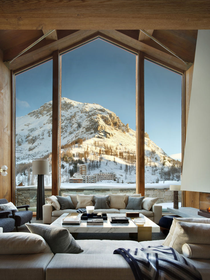 a living room filled with furniture and a large window covered in snow capped mountain view